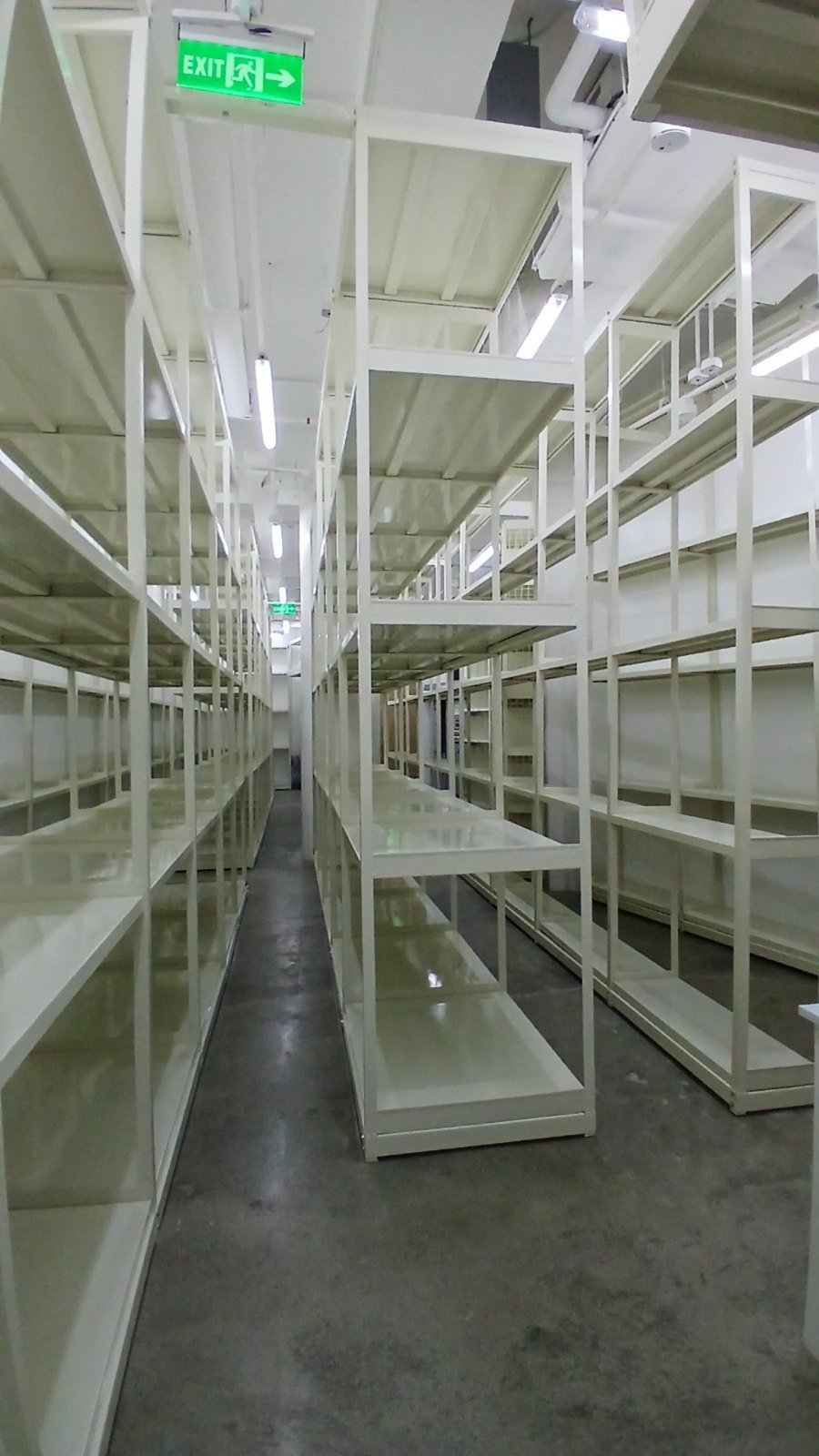 Rows of white steel storage racks in a warehouse aisle